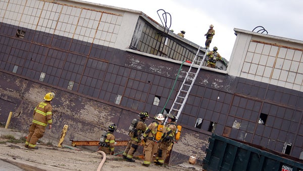 Firefighters use ladders to access a fire on the roof of a vacant industrial building on River Street in Buchanan Tuesday afternoon. Leader photo/CRAIG HAUPERT