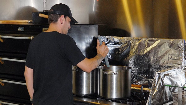 The PizzaWerks owner Aaron Wasmer stirs the sauce as the restaurant he opened last February. (Leader photo/SCOTT NOVAK)