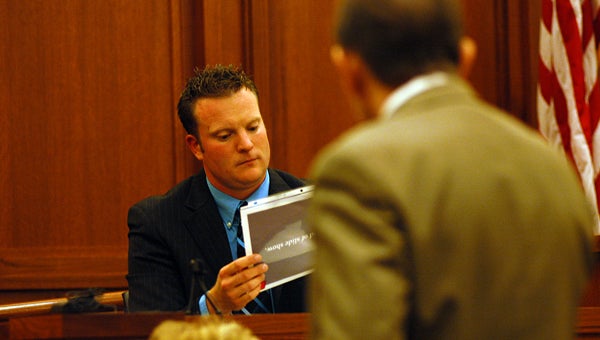 Kirk Deeleuw, forensic scientist with the Michigan State Police, looks at a picture of the scene of the crime during testimony Wednesday. Leader photo/CRAIG HAUPERT