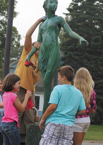 Abby Ickes, 19, Maddelynn Isprecht, 9, Matt Ickes, 9, Nathan Ickes, 13 and Andrew Ickes, 10 clean the “Dance of Creation” statue in Downtown Dowagiac.  About a dozen volunteers from the Dowagiac area and the Dogwood Fine Arts Festival gathered in downtown Dowagiac Saturday to wash, wax and buff Dowagiac’s 15 statues in preparation for winter. Leader Photo/AMBROSIA NELDON